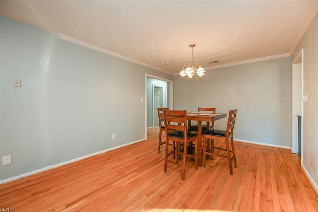 dining space featuring a notable chandelier, ornamental molding, and light hardwood / wood-style floors