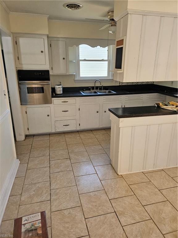 kitchen with sink, light tile patterned floors, ceiling fan, white cabinets, and oven