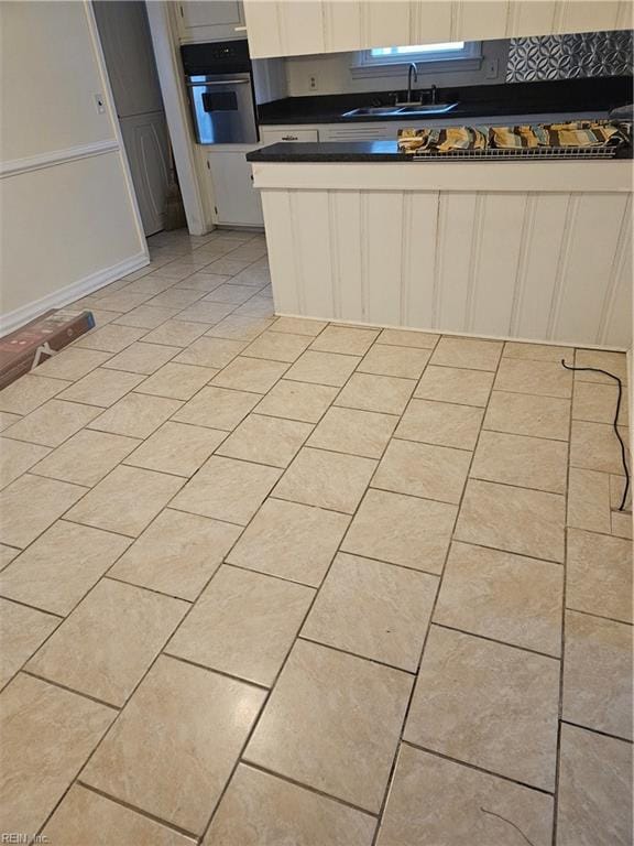 kitchen featuring white cabinetry, sink, oven, and light tile patterned flooring