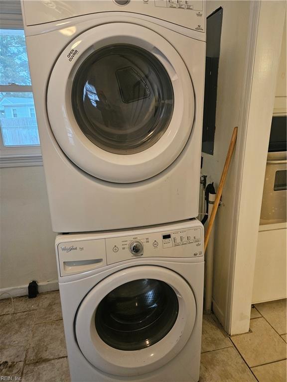 washroom featuring stacked washing maching and dryer and light tile patterned flooring