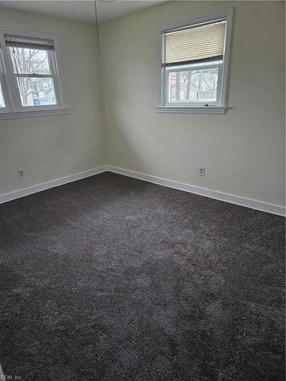 unfurnished room with dark carpet and a wealth of natural light