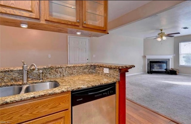 kitchen with sink, light colored carpet, dishwasher, ceiling fan, and light stone countertops