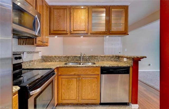 kitchen with light stone countertops, appliances with stainless steel finishes, sink, and kitchen peninsula