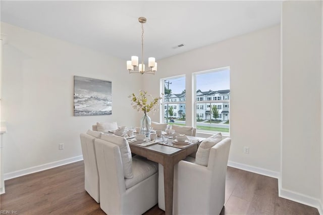 dining room with dark wood-type flooring and a chandelier