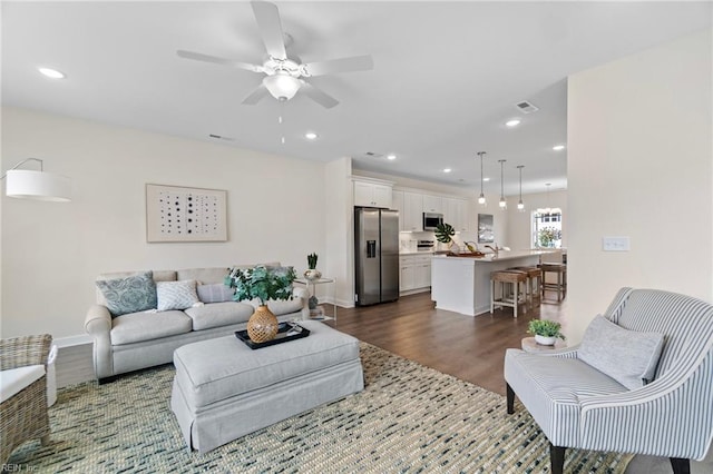 living room with dark wood-type flooring and ceiling fan