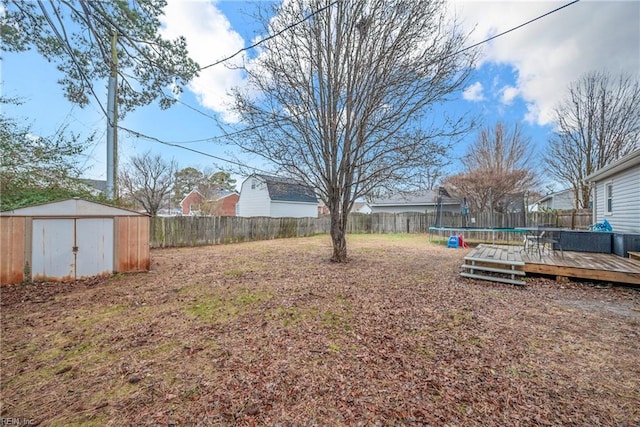 view of yard featuring a trampoline, a storage shed, and a wooden deck