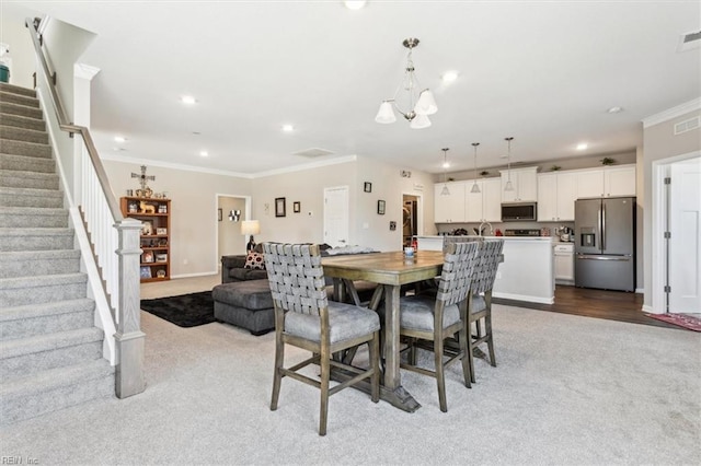 dining area featuring crown molding, light colored carpet, a chandelier, and sink