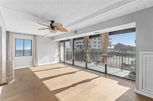 empty room with hardwood / wood-style floors, a textured ceiling, a wealth of natural light, and ceiling fan