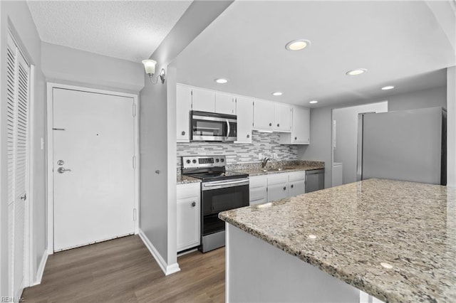 kitchen with appliances with stainless steel finishes, white cabinetry, dark hardwood / wood-style floors, tasteful backsplash, and light stone countertops