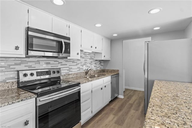 kitchen with stainless steel appliances, white cabinetry, sink, and light stone counters