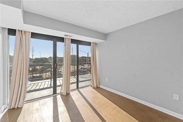 unfurnished room with hardwood / wood-style floors and a textured ceiling