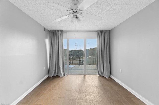 empty room with ceiling fan, wood-type flooring, and a textured ceiling