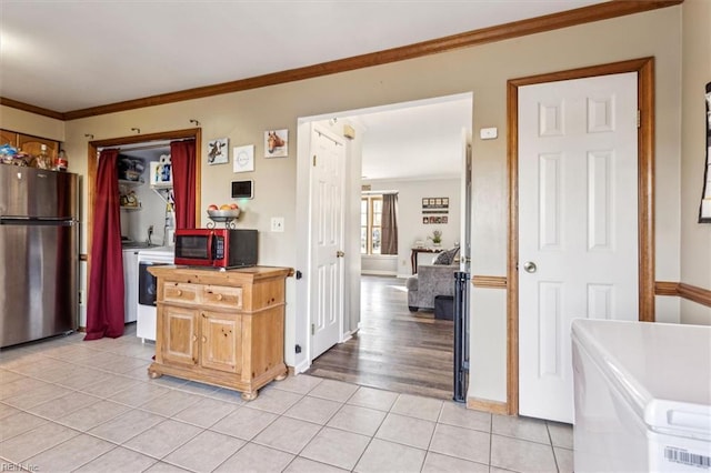 kitchen featuring butcher block counters, light tile patterned floors, ornamental molding, and stainless steel refrigerator