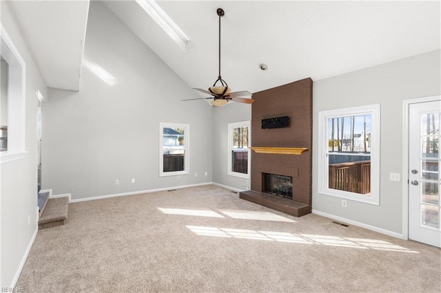 unfurnished living room featuring high vaulted ceiling, a fireplace, light colored carpet, and ceiling fan