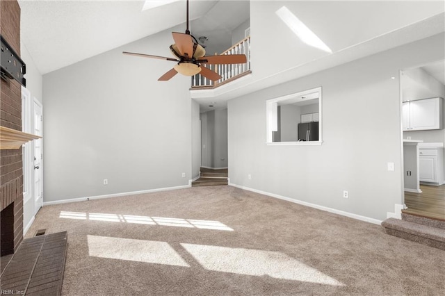 unfurnished living room with ceiling fan, carpet, high vaulted ceiling, and a fireplace