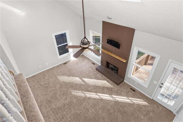 living room featuring high vaulted ceiling, a fireplace, light colored carpet, ceiling fan, and a textured ceiling