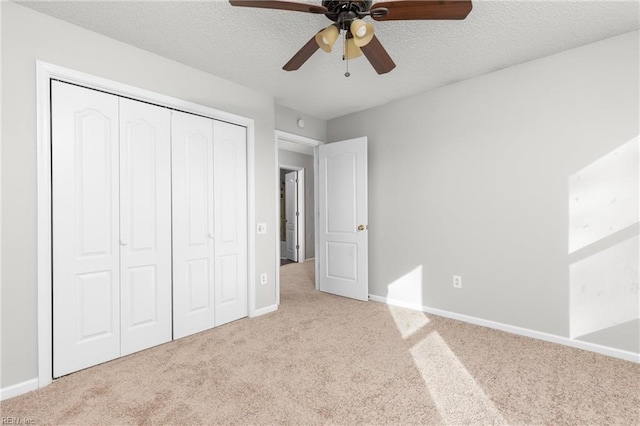 unfurnished bedroom with ceiling fan, light colored carpet, a closet, and a textured ceiling