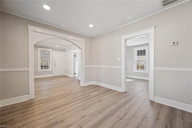 spare room with ornamental molding and light wood-type flooring