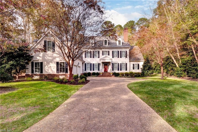 colonial inspired home with a garage and a front lawn