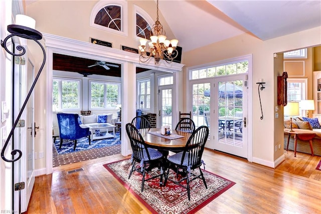 dining space featuring hardwood / wood-style flooring, high vaulted ceiling, a healthy amount of sunlight, and a chandelier