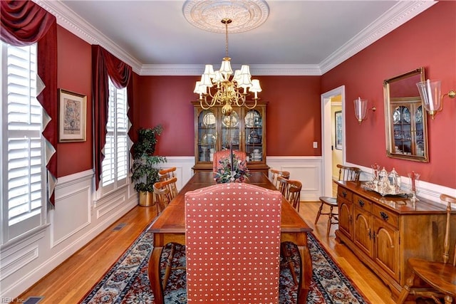 dining room with crown molding, light wood-type flooring, and a notable chandelier