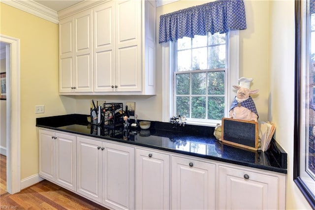 kitchen featuring hardwood / wood-style floors, a wealth of natural light, ornamental molding, and white cabinets