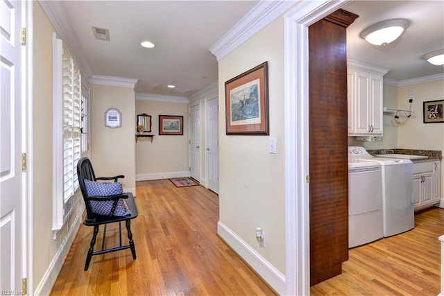 hall featuring crown molding, washer and clothes dryer, sink, and light hardwood / wood-style flooring