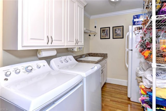 washroom with sink, crown molding, cabinets, independent washer and dryer, and light hardwood / wood-style floors