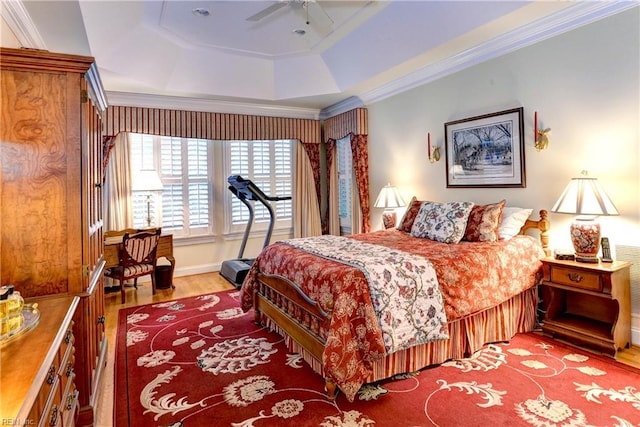 bedroom with crown molding, light hardwood / wood-style floors, a raised ceiling, and ceiling fan