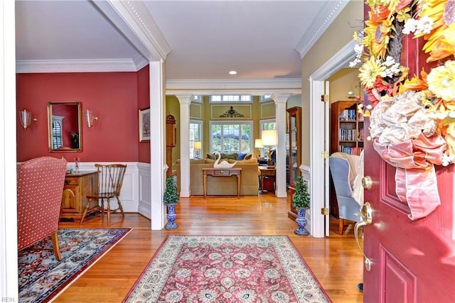 entryway featuring crown molding, wood-type flooring, and ornate columns