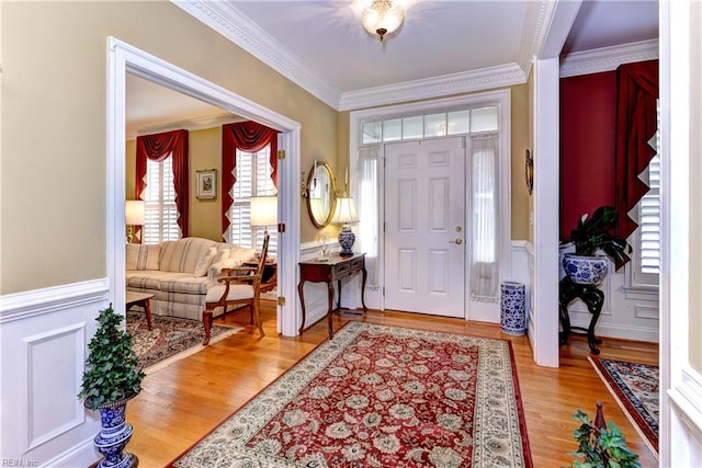 entryway with ornamental molding and light hardwood / wood-style flooring