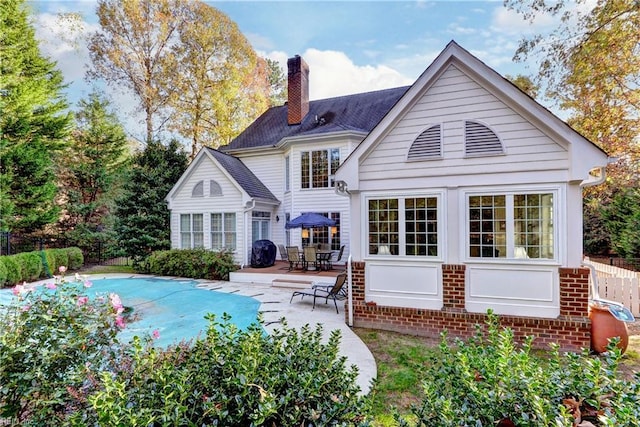 rear view of property with a covered pool and a patio