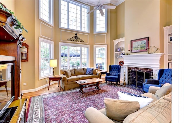 living room with hardwood / wood-style flooring, ceiling fan, a healthy amount of sunlight, and a brick fireplace