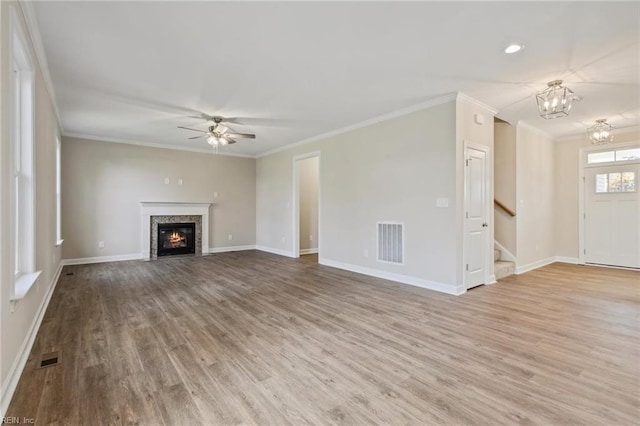 unfurnished living room with stairway, visible vents, wood finished floors, and ornamental molding