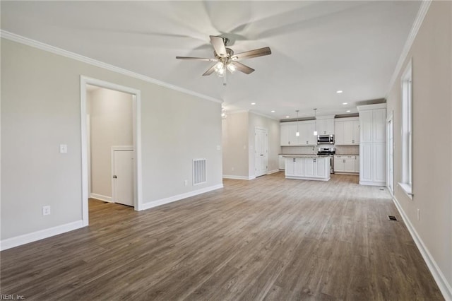 unfurnished living room featuring baseboards, wood finished floors, visible vents, and crown molding