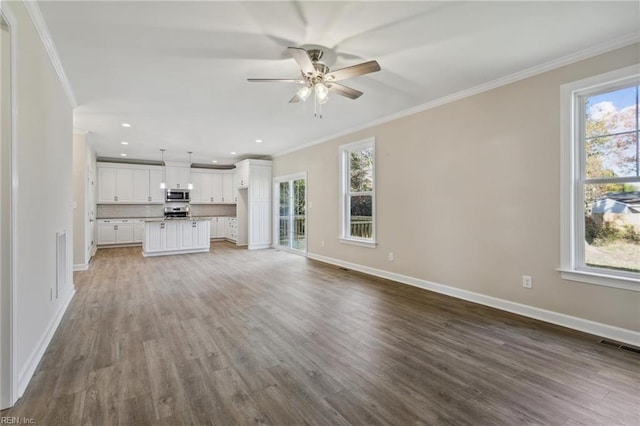 unfurnished living room with crown molding, baseboards, and wood finished floors