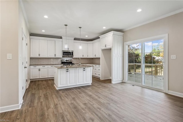 kitchen featuring crown molding, backsplash, appliances with stainless steel finishes, white cabinetry, and wood finished floors