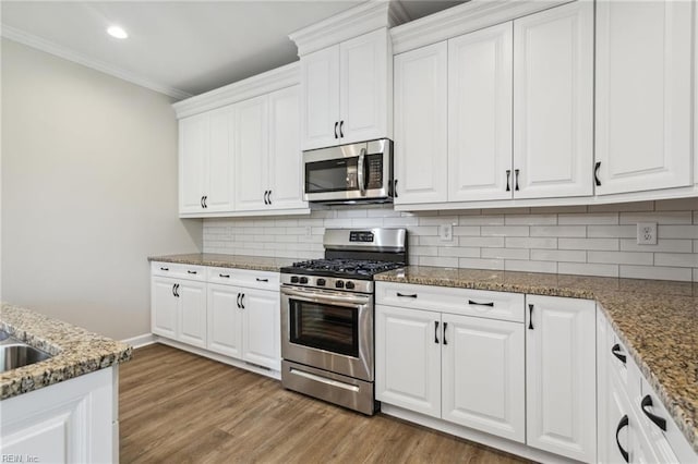 kitchen featuring crown molding, light wood-style flooring, decorative backsplash, appliances with stainless steel finishes, and white cabinets