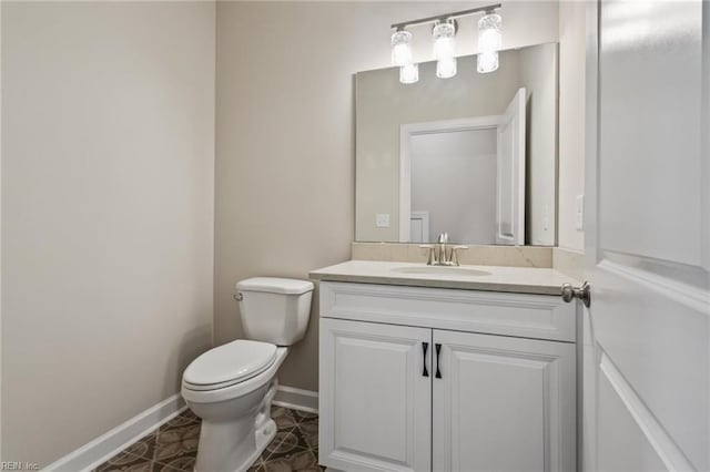 half bathroom featuring vanity, toilet, and baseboards