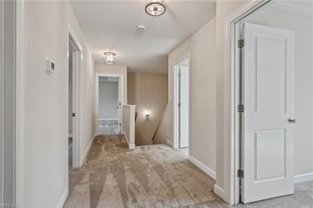 hall featuring carpet floors, an upstairs landing, and baseboards