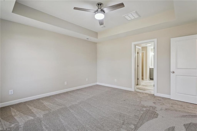 unfurnished bedroom featuring carpet floors, baseboards, visible vents, and a raised ceiling