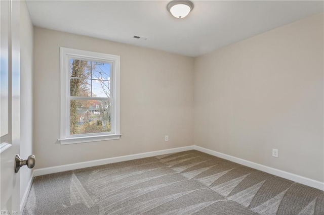 carpeted spare room featuring visible vents and baseboards