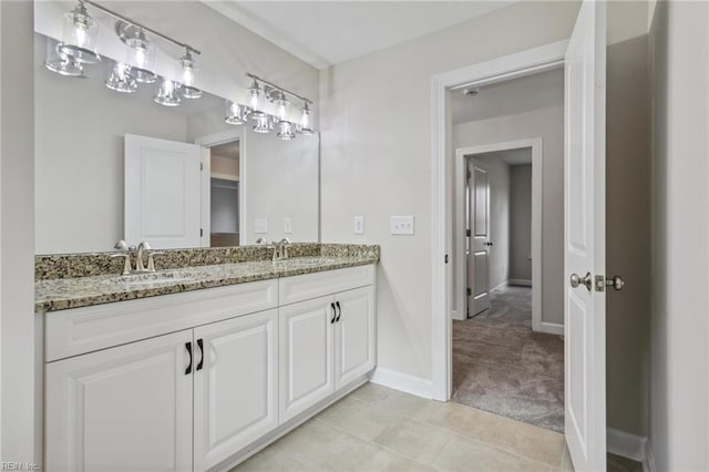 bathroom with double vanity, tile patterned flooring, baseboards, and a sink