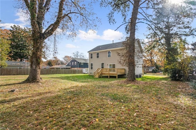 rear view of house featuring a yard, fence, and a wooden deck