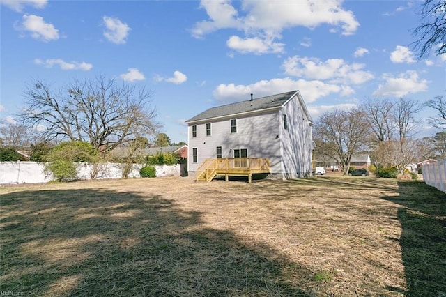 rear view of house featuring a yard, a wooden deck, and fence