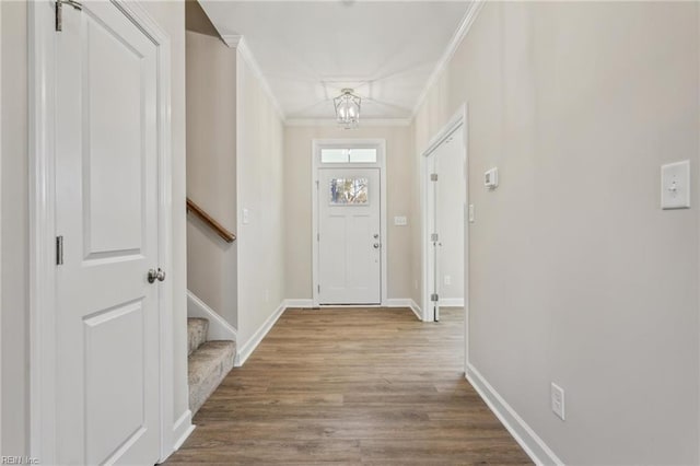 foyer with baseboards, wood finished floors, an inviting chandelier, stairs, and crown molding