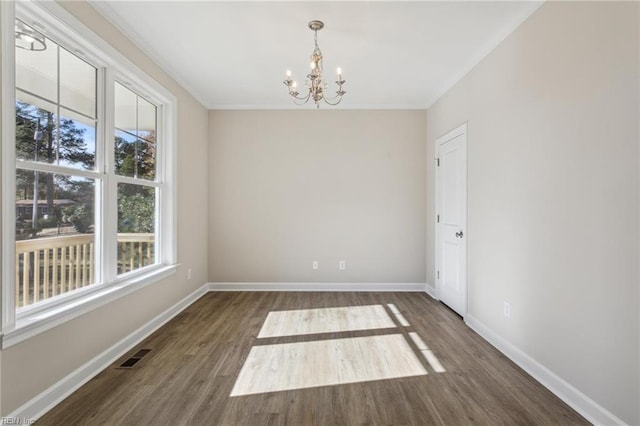 empty room featuring dark wood-style floors, crown molding, a notable chandelier, and baseboards