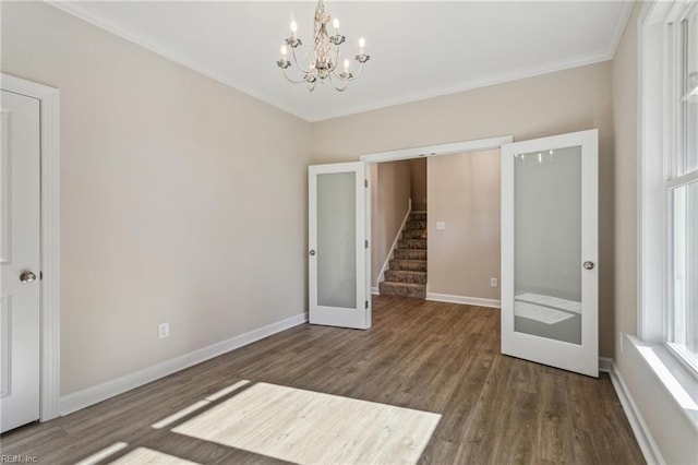 unfurnished bedroom featuring baseboards, ornamental molding, wood finished floors, an inviting chandelier, and french doors