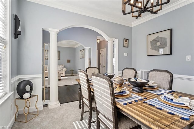 dining room with an inviting chandelier, ornamental molding, light carpet, and ornate columns