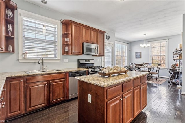 kitchen featuring sink, dark wood-type flooring, hanging light fixtures, stainless steel appliances, and a kitchen island